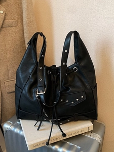 Vintage large black tote bag with silver studs and buckles on a silver suitcase