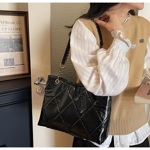 Détail d'un sac cabas en cuir verni matelassé noir avec accents de chaîne dorée élégants