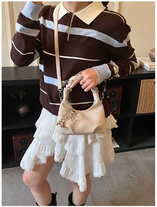 Detail of cream crossbody bag with floral embroidery and heart pendant decoration