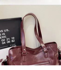 Close-up of wine red glossy leather tote bag with silver rivets and front zipper pocket