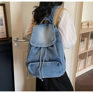 Détail du sac à dos en jean délavé bleu avec rabat supérieur et fermeture à cordon