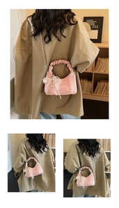 Detail of pink crescent bag with pleated handle, chain strap, and lace pearl bow charm