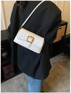 Vista laterale della borsa bianca in pelle sintetica con fibbia d'oro su blazer nero