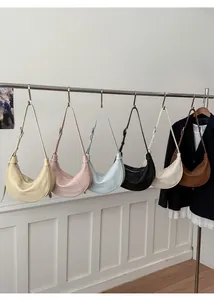 Minimalist half-moon underarm bags in six colors shown hanging in a boutique display