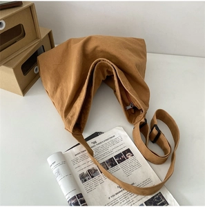 Detail of earthy brown canvas tote bag featuring adjustable strap and secure metal zipper