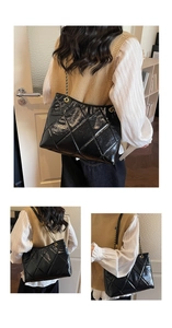 Detailed view of black quilted leather tote bag with gold chain strap on model