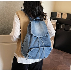 Vue arrière d'un mannequin portant le sac à dos vintage en denim bleu avec rabat et cordon