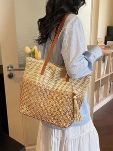 Fashionable woven straw tote bag with brown leather straps and stylish tassel pendant