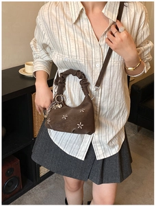 Detail of dark brown vintage bag with white flower embroidery and heart charm detail
