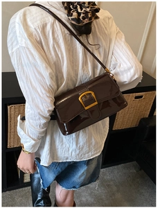 Dettaglio della borsa sottobraccio in pelle lucida marrone scuro con fibbia quadrata d'oro