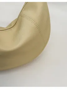 Detail of light beige crescent bag showing pebbled leather texture and double stitching