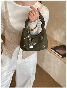Detail of dark green denim dumpling bag with star embroidery and metallic charms