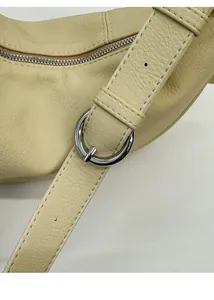 Detail of adjustable long shoulder strap with silver buckle on cream yellow leather bag