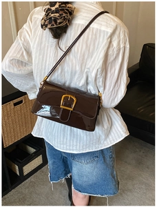 Borsa a spalla in pelle verniciata marrone scuro con grande fibbia dorata vista indossata