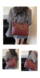 Detail view of burgundy quilted patent leather bag with gold chain strap on shoulder