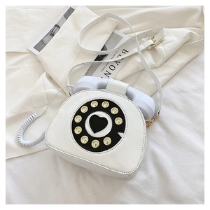 Detalle de un bolso bandolera creativo blanco con forma de teléfono vintage y dial