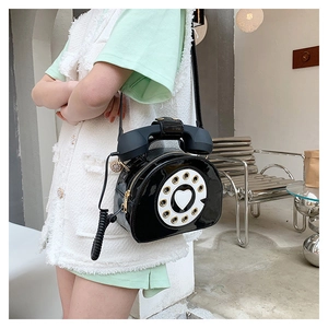 Primer plano de un bolso creativo con forma de teléfono retro en piel sintética negra brillante
