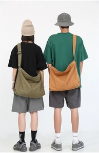 Detailed view of oversized washed canvas messenger bags in olive green and mustard yellow