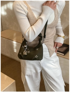Detail of olive green handbag with silver star studs and heart lock pendant on the strap