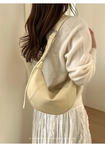 Detail of cream crescent shoulder bag with pebbled leather texture and metal buckle