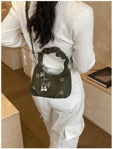 Detail view of olive green ruched handbag with star embroidery and metal charms