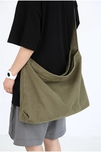 Detailed view of army green canvas crossbody bag on model showing large capacity and drape