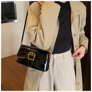 Borsa a spalla in pelle verniciata nera con fibbia dorata, indossata per un look chic