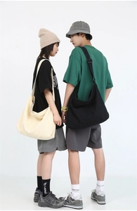 Large minimalist canvas messenger bag in cream and black shown on models for size scale