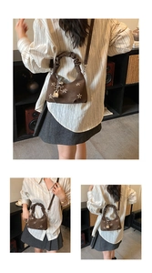 Detail of a brown shoulder bag featuring star embroidery and a pleated handle design