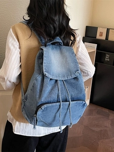 Sac à dos vintage en denim bleu avec fermeture à rabat et cordon porté par le mannequin