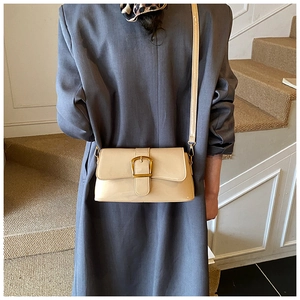 Dettaglio della borsa a tracolla in vernice beige con fibbia dorata indossata da modella