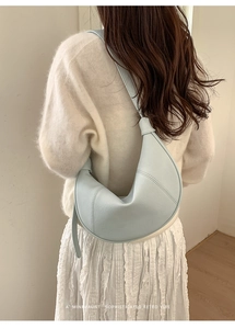 Detail view of light blue leather crescent shoulder bag with minimalist knotted strap