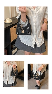 Detail of black cloud bag featuring star embroidery and metallic heart bow charms