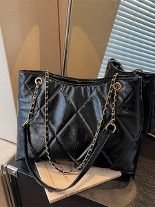 Sac fourre-tout noir verni avec chaîne dorée dans un cadre de café élégant