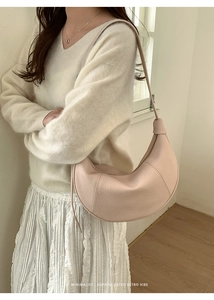 Close-up of minimalist beige crescent shoulder bag with elegant leather stitching details