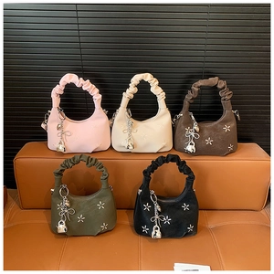 Detail of five multi-colored pleated handle handbags with star embroidery and metal charms