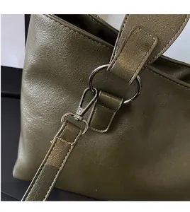 Detail of dark olive green tote bag featuring metallic swivel lobster clasp and stitching