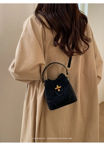 Detailed view of black bucket bag with gold clasp and top handle for a retro vibe
