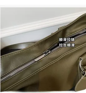 Detailed close-up of high-quality dark grey metal zipper on olive green leather tote bag