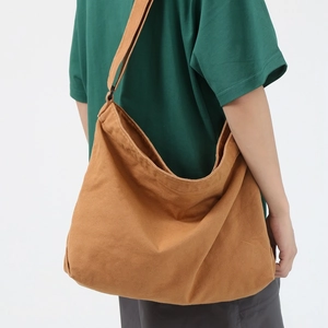 Large casual brown washed canvas messenger bag for women shown on a model from a side view
