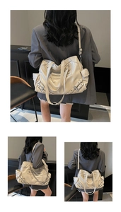 Detail view of cream tote bag with metal stud accents and multi-zippered pockets
