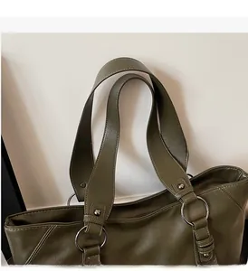 Detail of olive green tote bag showing silver ring strap connectors and stitching