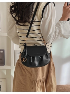 Détail du sac à bandoulière plissé noir avec boucles dorées et lettrage embossé