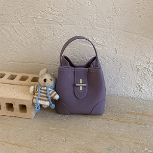 Détail du sac seau en cuir violet avec fermoir tournant argenté et breloque ourson