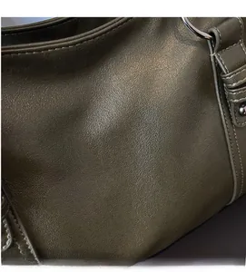 Close-up of olive green tote bag featuring lychee grain texture and metal ring hardware