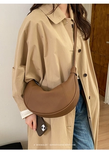Fashionable brown crescent shoulder bag shown on a model wearing a classic trench coat