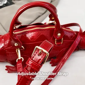 Detail des verstellbaren Schultergurts mit goldener Metallschnalle an roter Kroko-Tasche