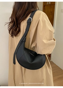 Detail of minimalist black crescent bag with textured leather and adjustable wide strap