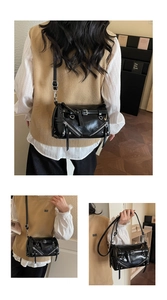Detail view of black glossy leather baguette bag with silver zippers and buckles