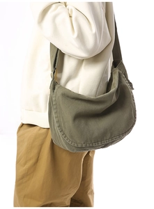 Detailed view of army green canvas messenger bag worn by a model in studio
